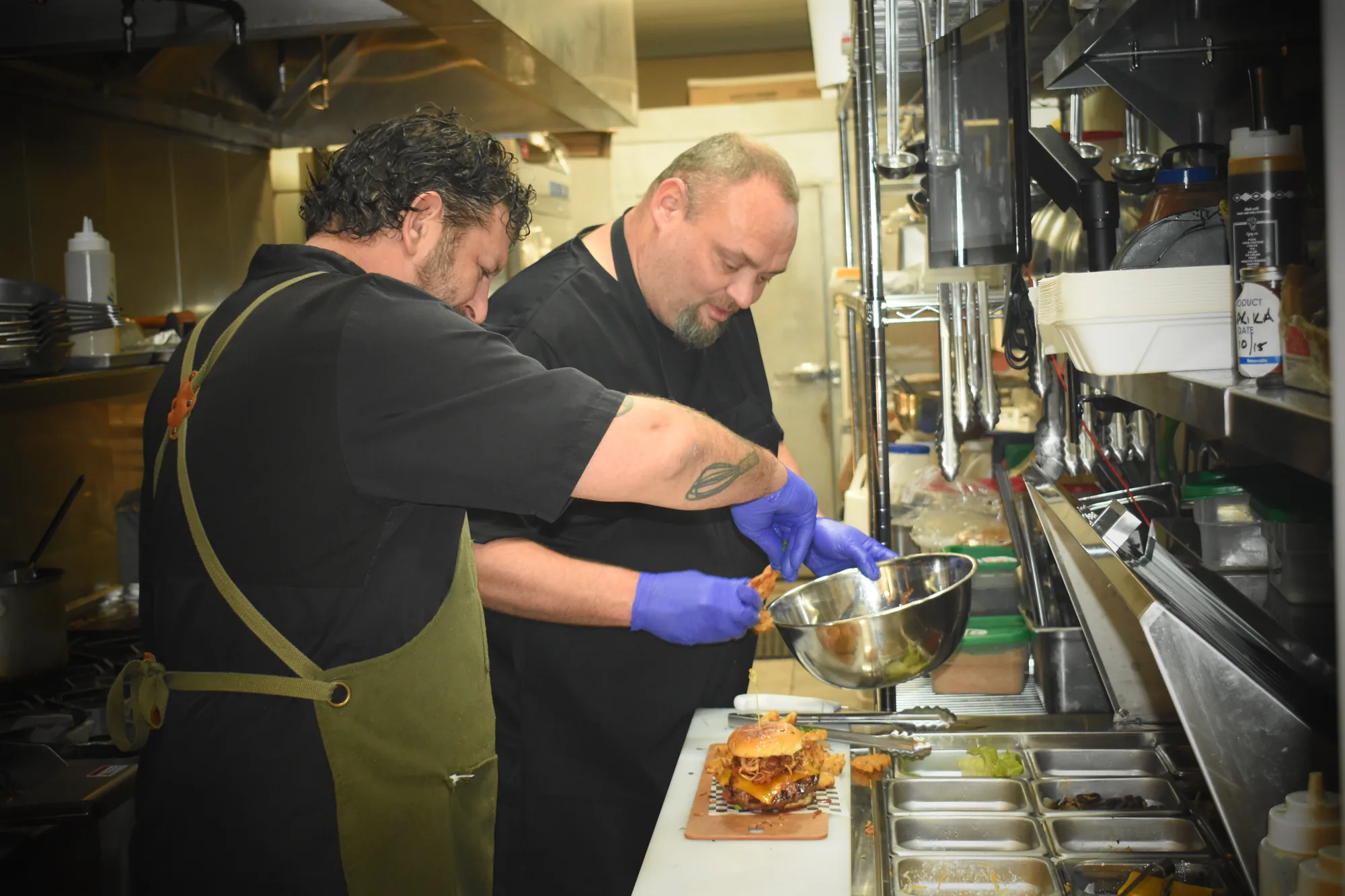 Two Rush Hour chefs plating burgers in the kitchen
